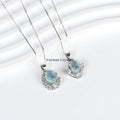 Two elegant silver necklaces with aquamarine blue oval pendants surrounded by sparkling stones on white background