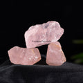 Three natural rose quartz crystal stones with soft pink hues displayed on black fabric background