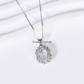 Delicate silver pendant with oval blue moonstone surrounded by clear crystals on fine chain against white background