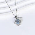 Elegant silver pendant necklace with aquamarine blue oval stone surrounded by sparkling halo stones on white background