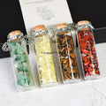 Chakra healing chip stones in glass wishing bottles with cork stoppers, arranged in a row on a neutral surface