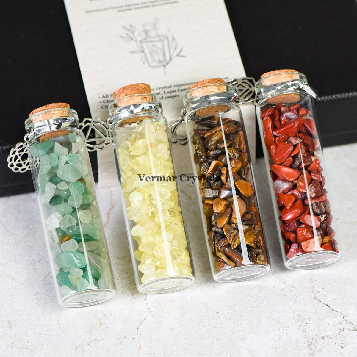 Chakra healing chip stones in glass wishing bottles with cork stoppers, arranged in a row on a neutral surface