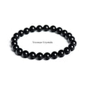 Stretchy bracelet made of polished 8mm black obsidian round beads arranged in a circle on a white background