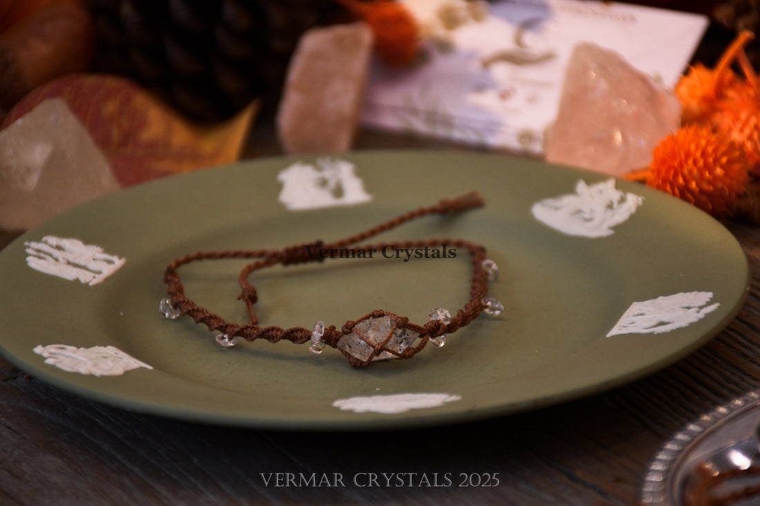 Handcrafted Herkimer Diamond bracelet with clear stones on braided brown cord resting on textured surface and paper background