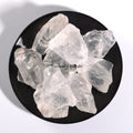Natural clear quartz raw crystal stones arranged on a black round dish against a white background