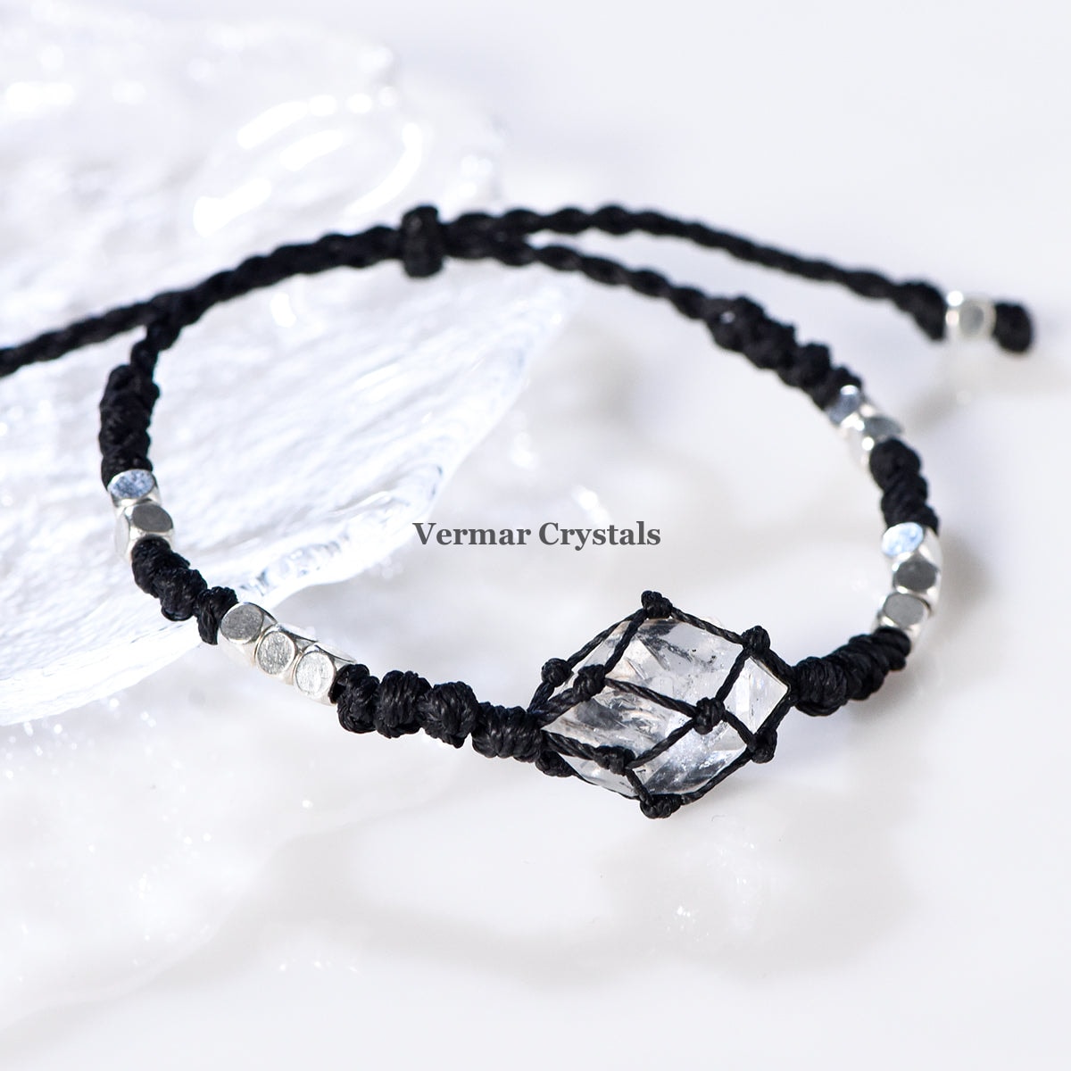 Handcrafted Herkimer Diamond crystal wrapped in black braided cord with silver beads on an adjustable bracelet against white background