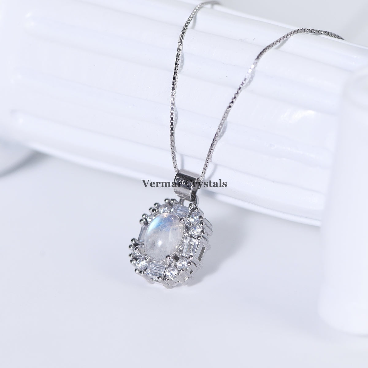 Elegant silver pendant featuring an oval blue moonstone surrounded by sparkling clear gemstones on a delicate chain