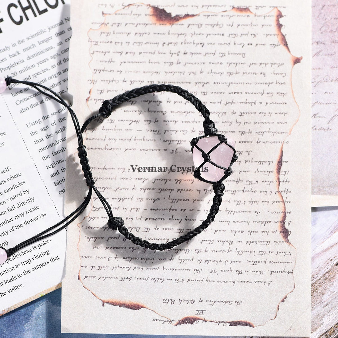 Handmade bracelet with a natural tumbled rose quartz stone wrapped in black macrame cord on a white surface