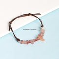 Handmade bracelet with natural strawberry quartz chip beads and a brown leather adjustable cord on a blue and white background