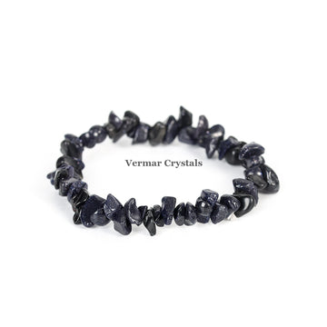 Stretchy bracelet made of irregular polished blue goldstone chip beads arranged in a circle on a white background