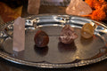 Four polished and raw love and happiness crystals on decorative silver tray with warm ambient lighting