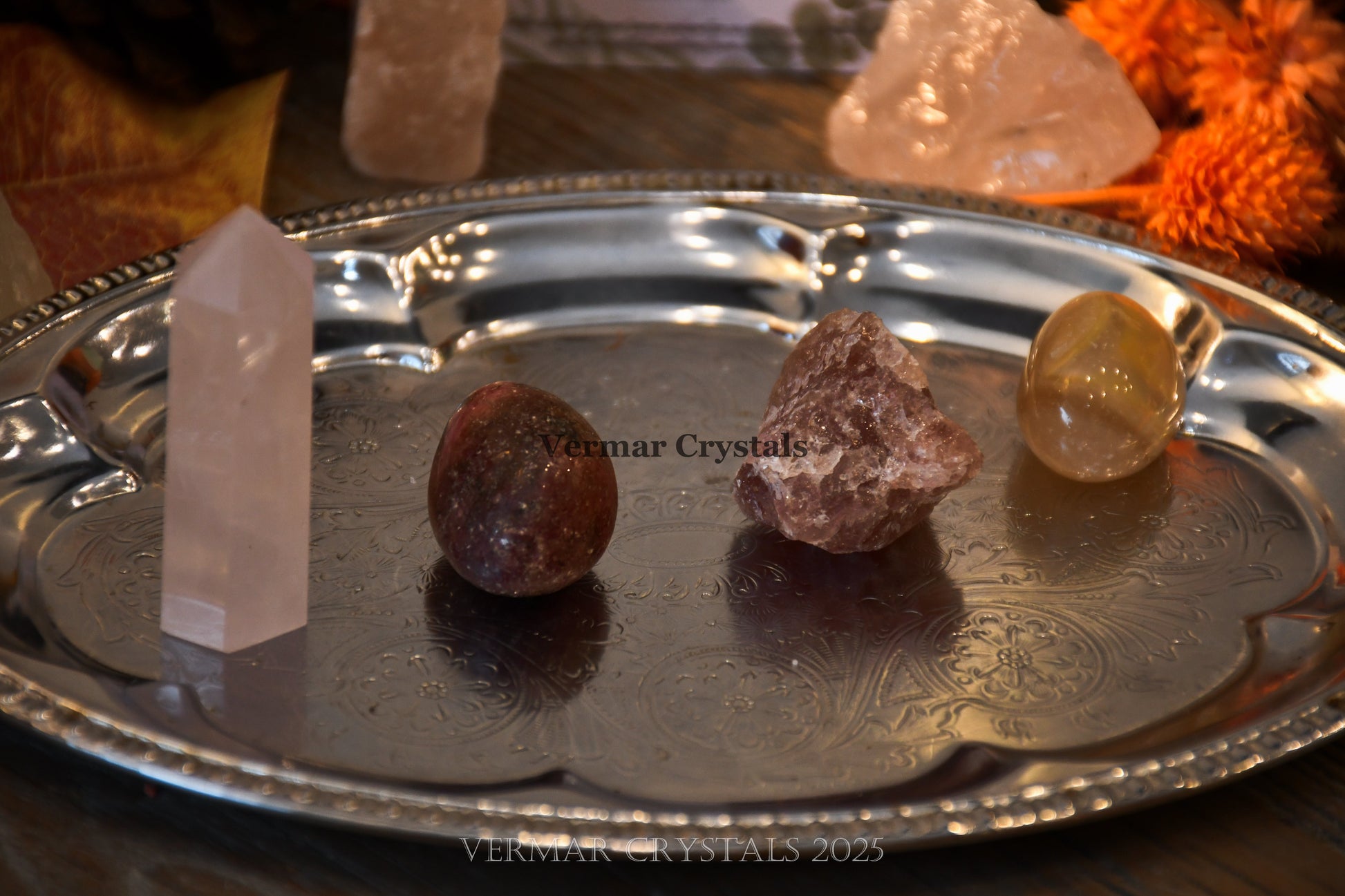Four polished and raw love and happiness crystals on decorative silver tray with warm ambient lighting