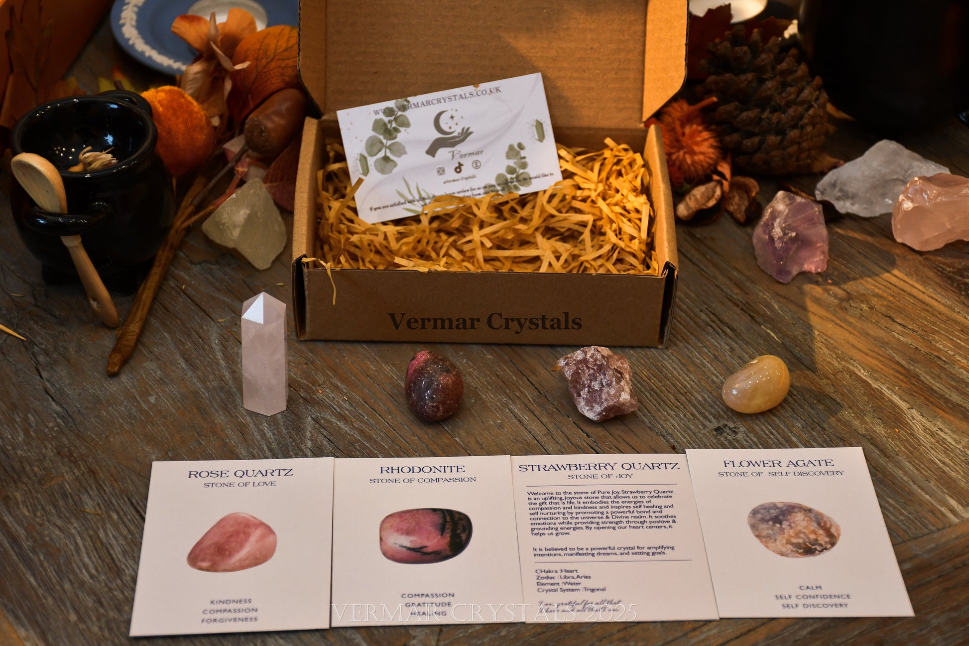 Love & Happiness crystal set displayed on wooden table with rose quartz, rhodonite, strawberry quartz, flower agate, and informational cards
