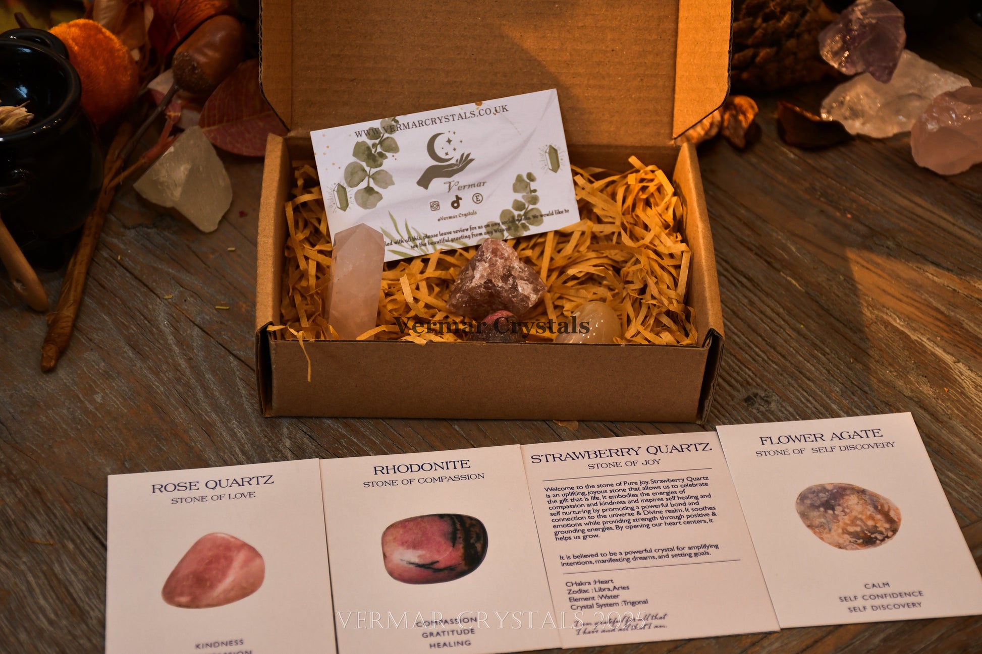 Love & Happiness Crystal Set with rose quartz, rhodonite, strawberry quartz, and flower agate stones in a gift box on wooden table