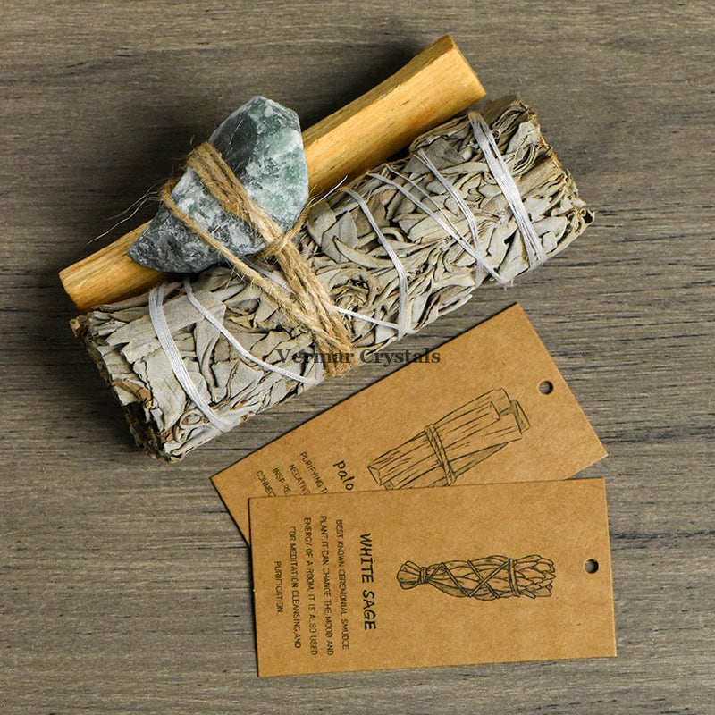 Bundle of Mexican white sage, palo santo stick, and green aventurine stone with kraft tags on wooden surface