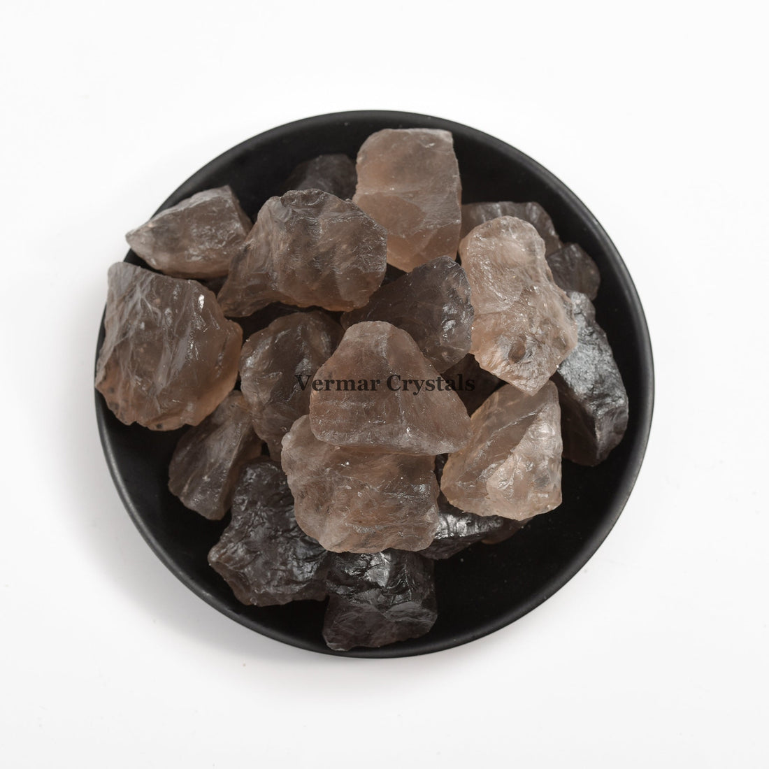 Natural smoky quartz crystal stones in varying shades of brown and gray arranged in a black dish on white background