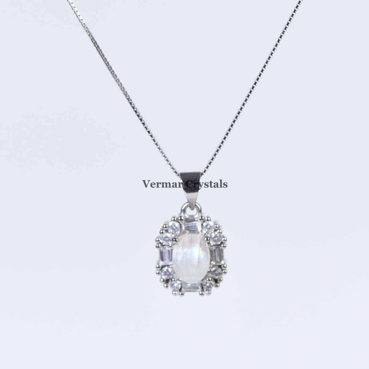 Delicate silver pendant featuring an oval blue moonstone surrounded by small clear gemstones on a fine chain