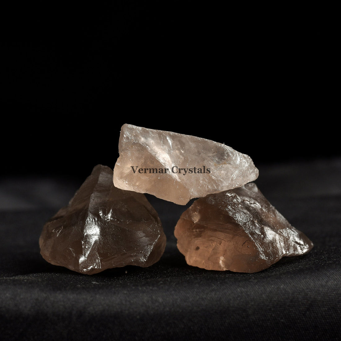 Natural smoky quartz crystal stones in varying shades of brown and gray arranged in a black dish on white background