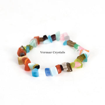 Handmade stretchy bracelet made of polished colorful chip stones arranged in a circular shape on white background