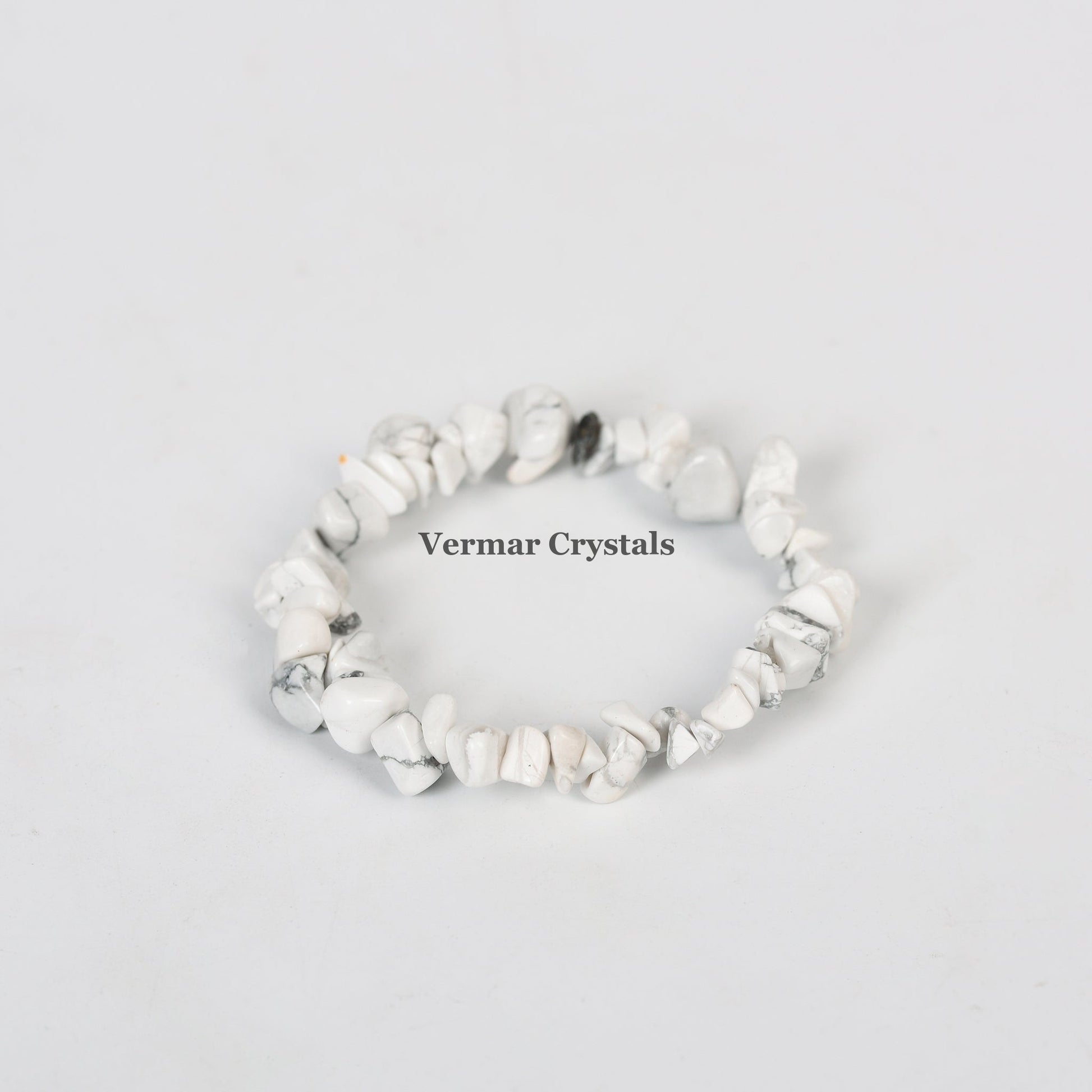 Stretchy bracelet made of irregular white turquoise chip stones with gray veining on a light gray background