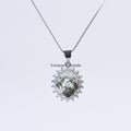 Silver pendant necklace with green phantom quartz centerpiece surrounded by sparkling clear stones on chain
