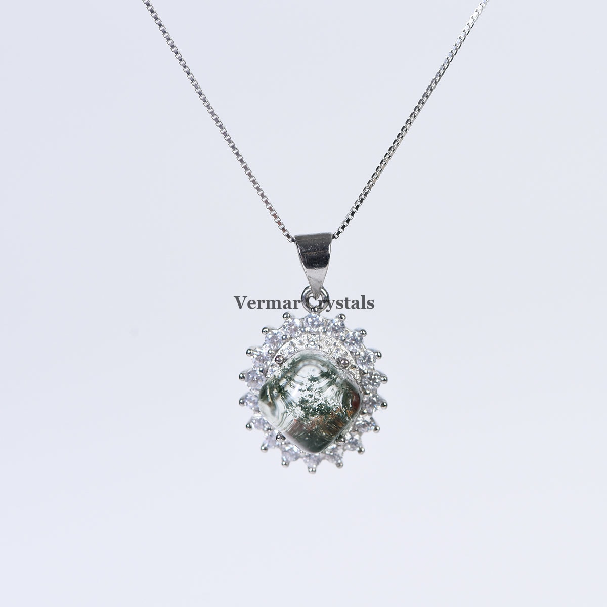 Silver pendant necklace with green phantom quartz centerpiece surrounded by sparkling clear stones on chain