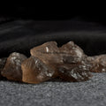 Group of natural smoky quartz crystal stones with translucent brown hues on a textured gray surface