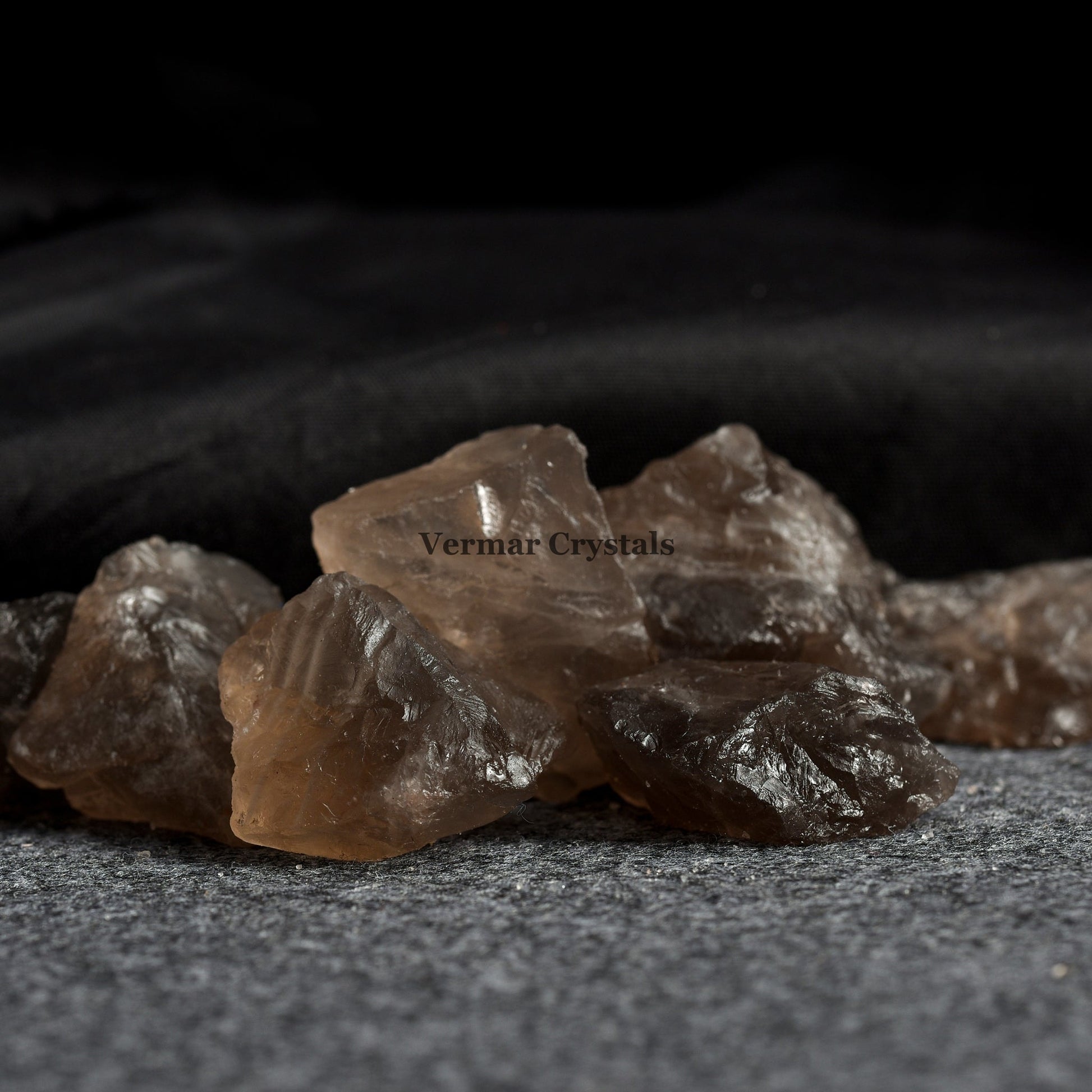 Group of natural smoky quartz crystal stones with translucent brown hues on a textured gray surface