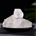 Natural clear quartz stones with a translucent appearance displayed on a black dish against a dark background