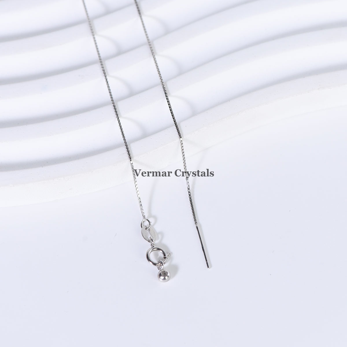 Delicate silver chain necklace with spring clasp and fine bar on white textured background