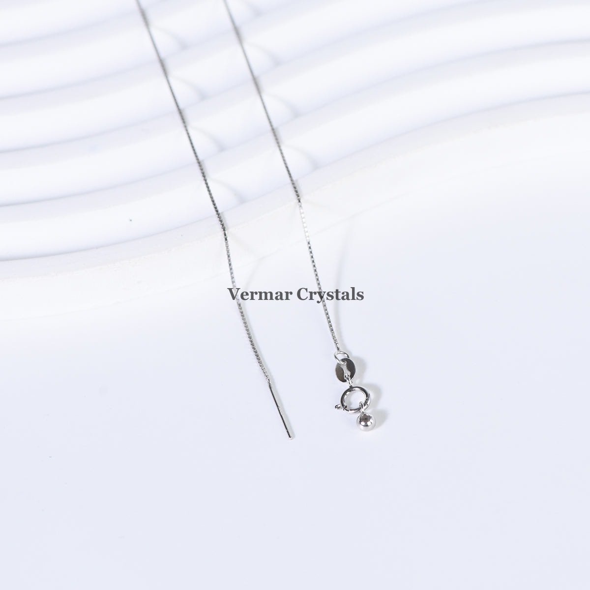 Elegant silver threader necklace with small polished silver details on white textured background