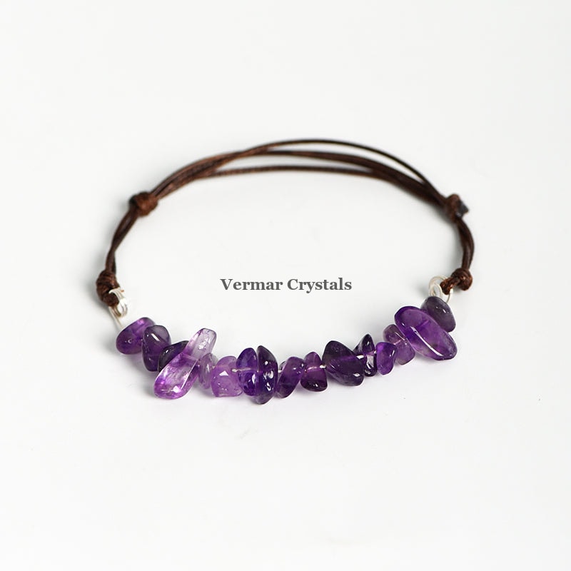 Handmade bracelet with irregular polished purple amethyst chip beads woven on an adjustable brown leather cord on white background