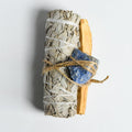 Bundle of white sage, Palo Santo stick, and blue Lapis Lazuli stone tied with natural twine for healing rituals.