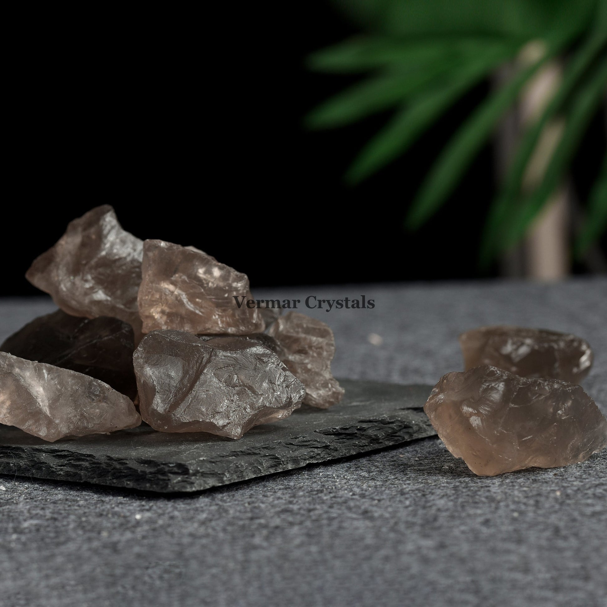 Collection of irregular smoky quartz crystal stones with translucent brown tones on a textured slate surface