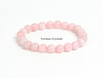 Stretchy bracelet made of smooth round light pink rose quartz beads arranged in a circle on a white background