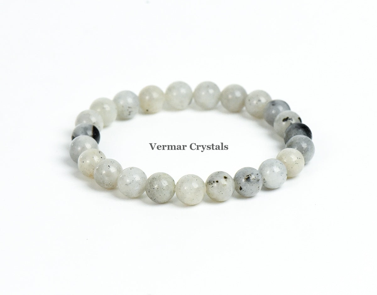 Stretchy bracelet made of smooth round pale gray and white labradorite beads arranged in a circle on a white background