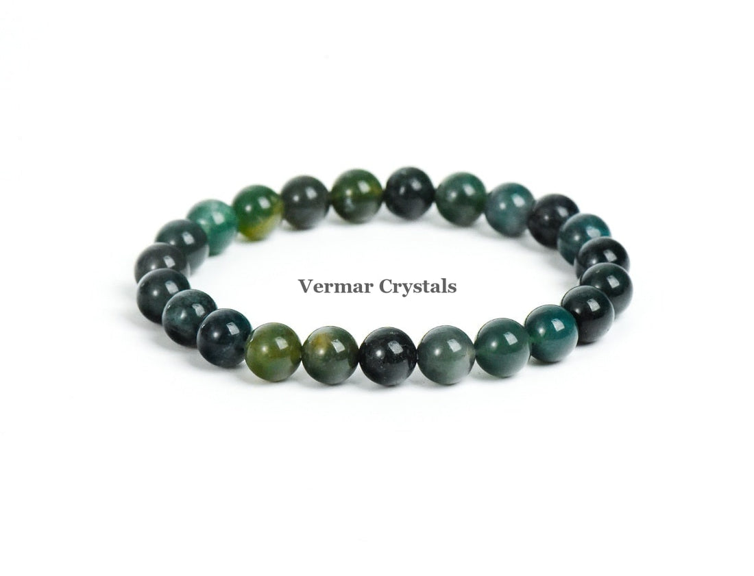Stretchy bracelet made of polished green and dark moss agate beads arranged in a circular shape on white background