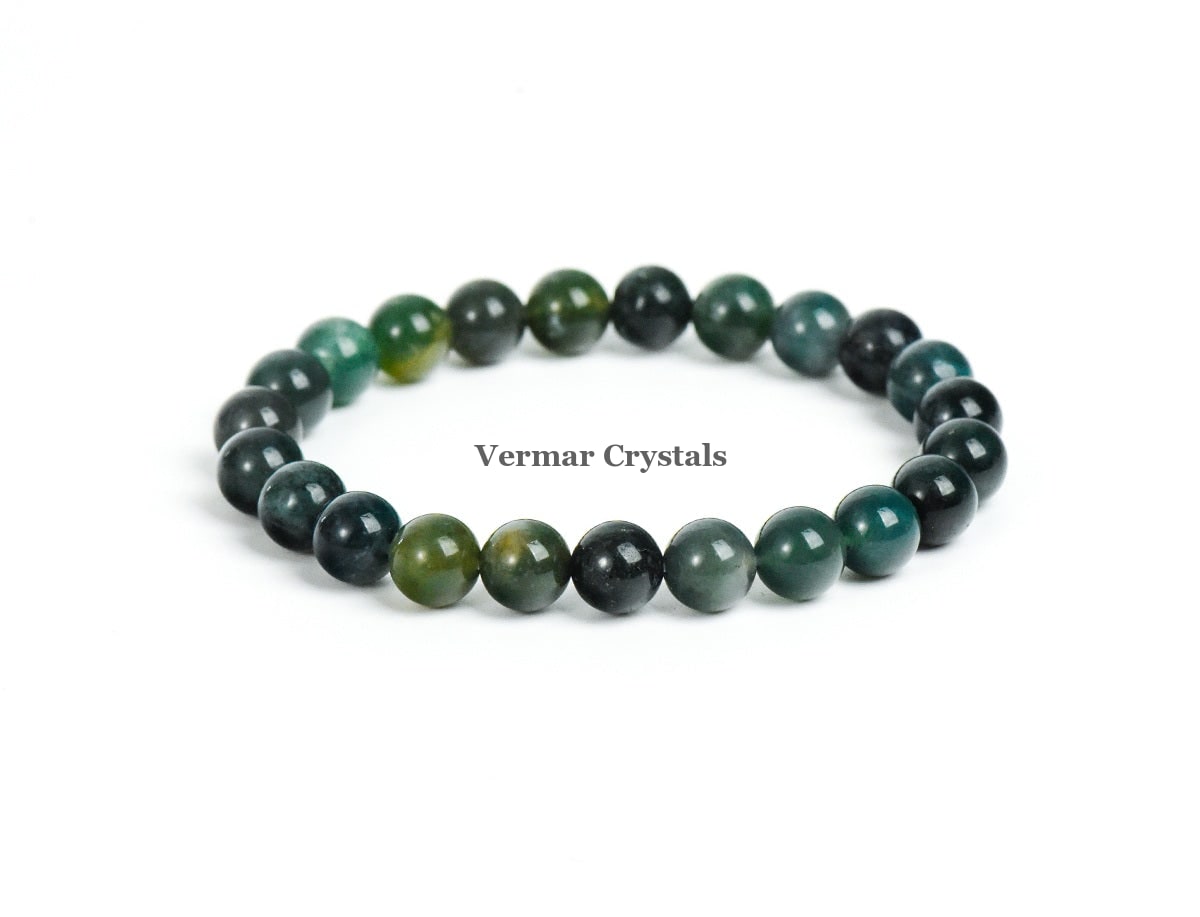 Stretchy bracelet made of polished green and dark moss agate beads arranged in a circular shape on white background