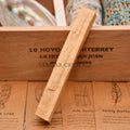 Single 10cm natural palo santo stick resting on wooden box with illustrated information cards below