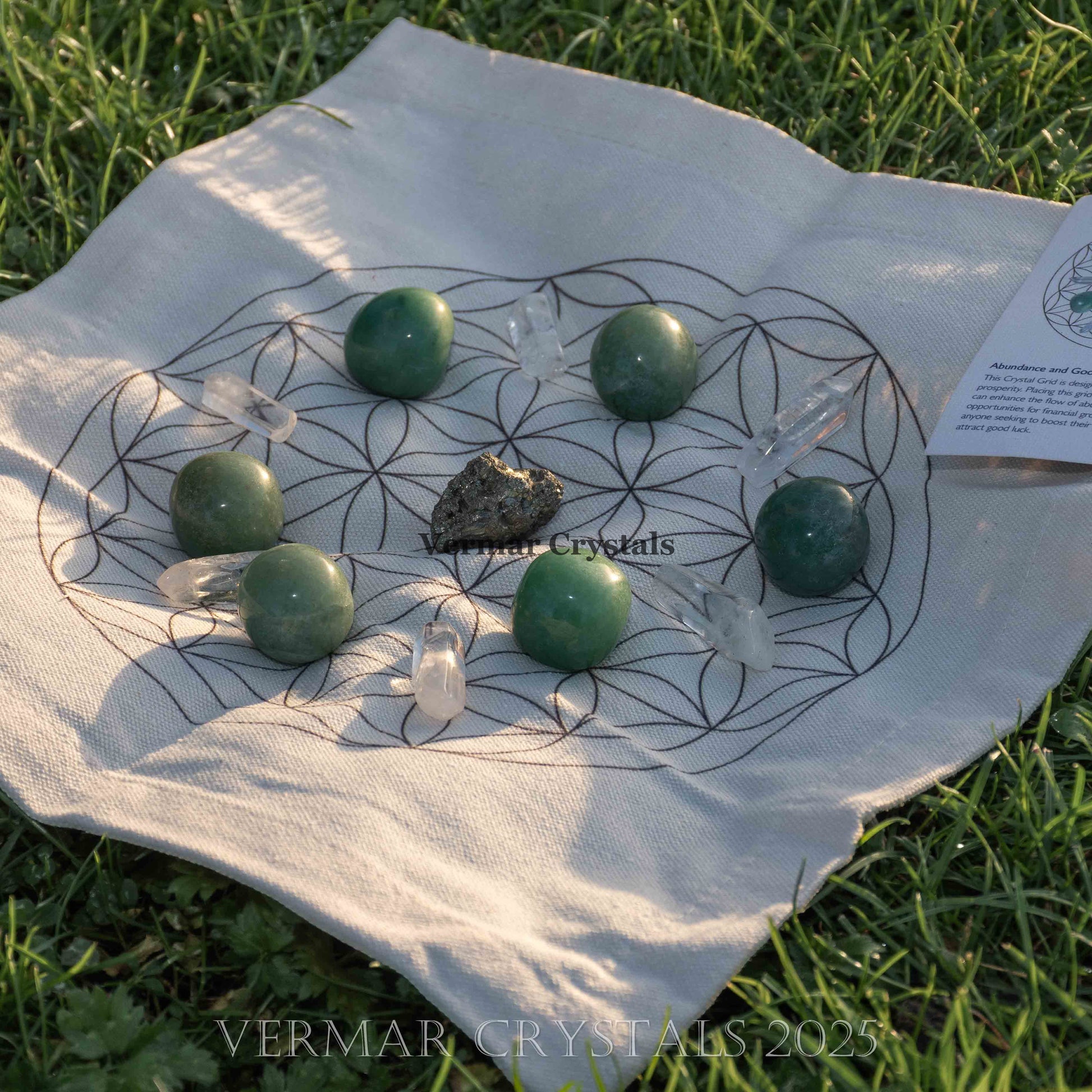 Abundance and good luck connection grid set with green and clear crystals on fabric cloth laid on grass background