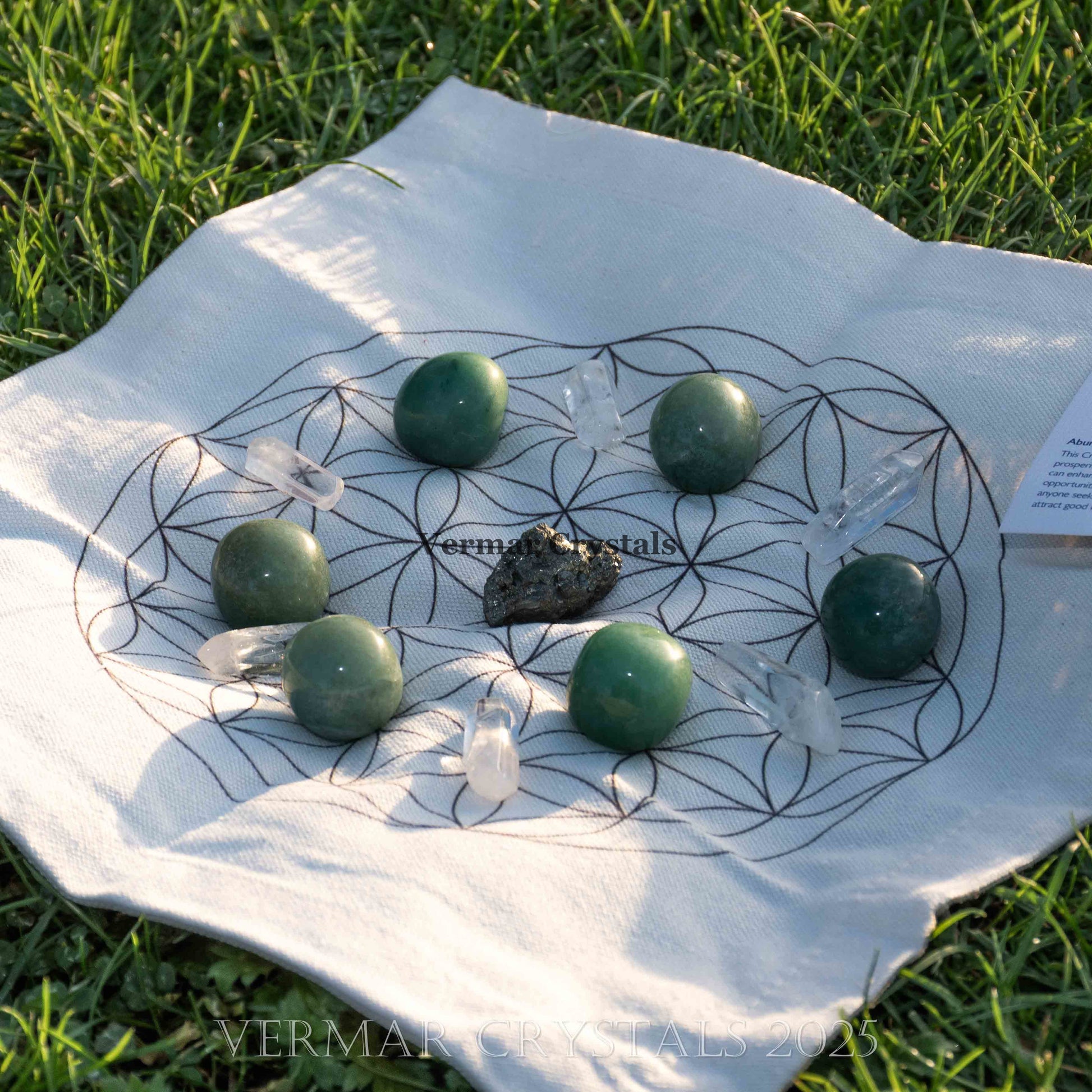 Abundance and good luck crystal grid set with green aventurine stones, clear quartz points, and fabric cloth on grass background