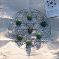Abundance and good luck connection grid set with green stones, clear crystals, and a central pyrite piece on fabric cloth