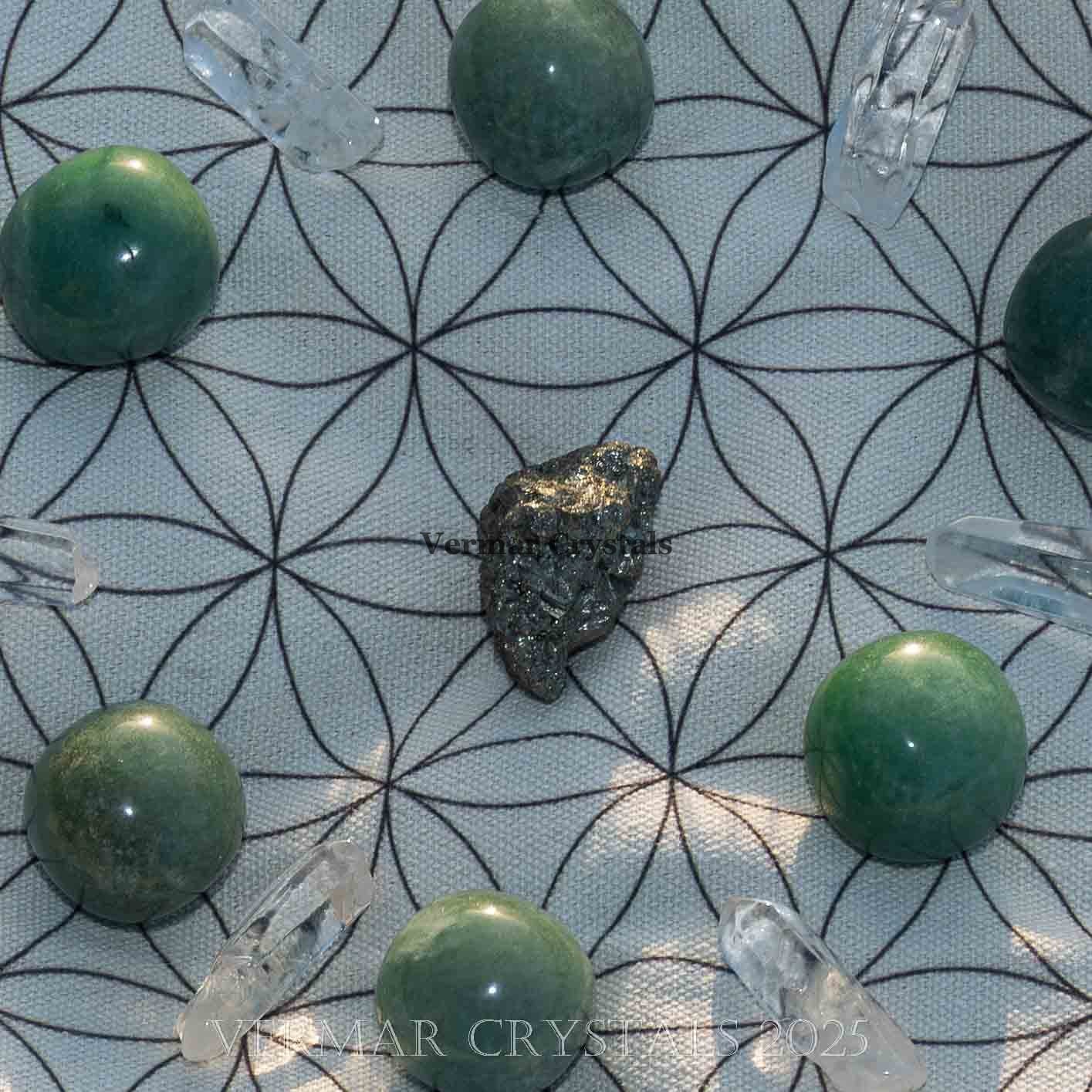 Abundance and good luck crystal grid with green aventurine and clear quartz points on fabric cloth background