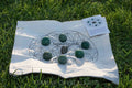 Abundance and good luck crystal grid set with green stones and black central crystal on fabric cloth outdoors on grass