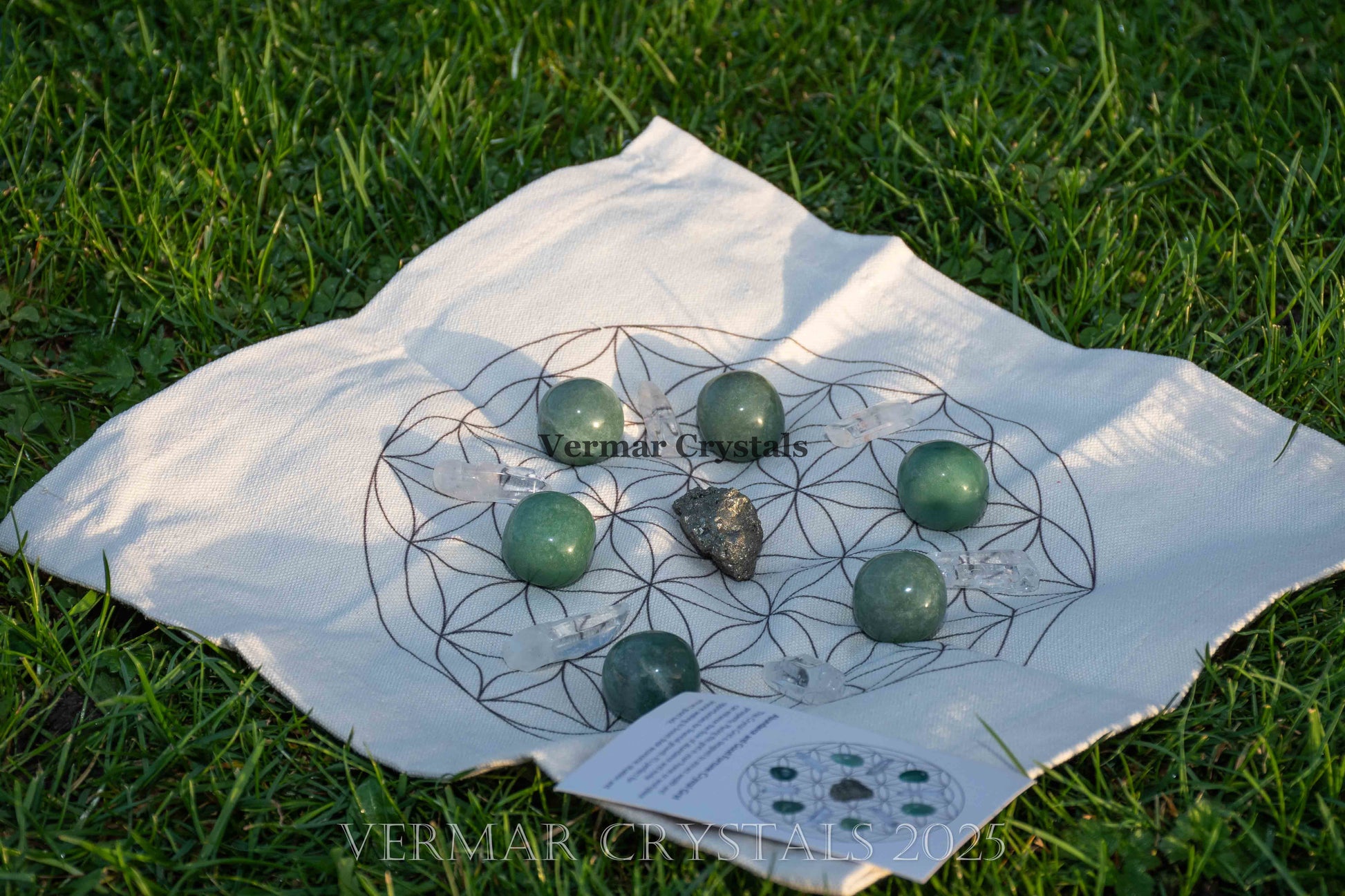 Abundance and good luck crystal grid set featuring green stones on a fabric cloth with geometric design outdoors on grass