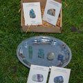 Set of natural intuition and wisdom crystals including fluorite, lapis lazuli, apatite, and labradorite stones on silver tray and packaging cards