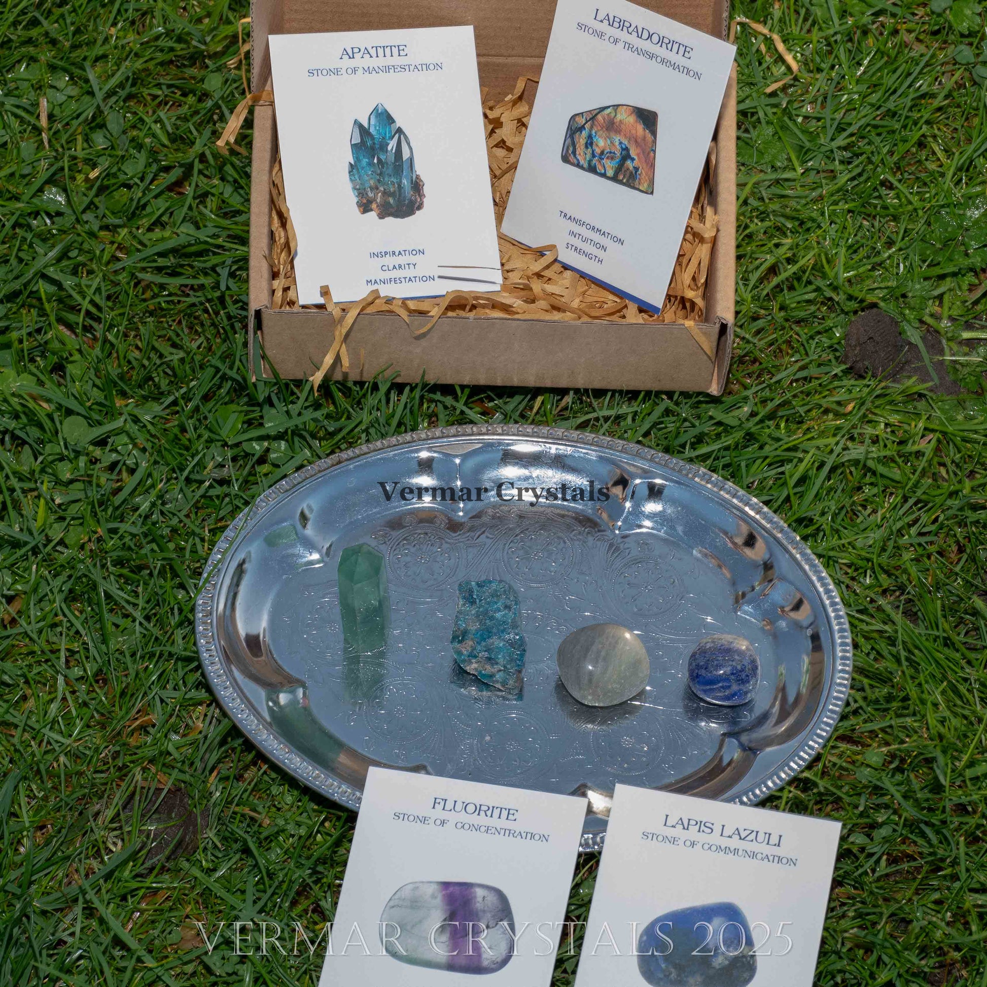 Set of natural intuition and wisdom crystals including fluorite, lapis lazuli, apatite, and labradorite stones on silver tray and packaging cards