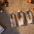 Three clear quartz crystal towers with pointed tips on textured burlap background with dried decorative elements