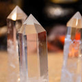 Three natural clear quartz towers with pointed tips standing upright on blurred warm background