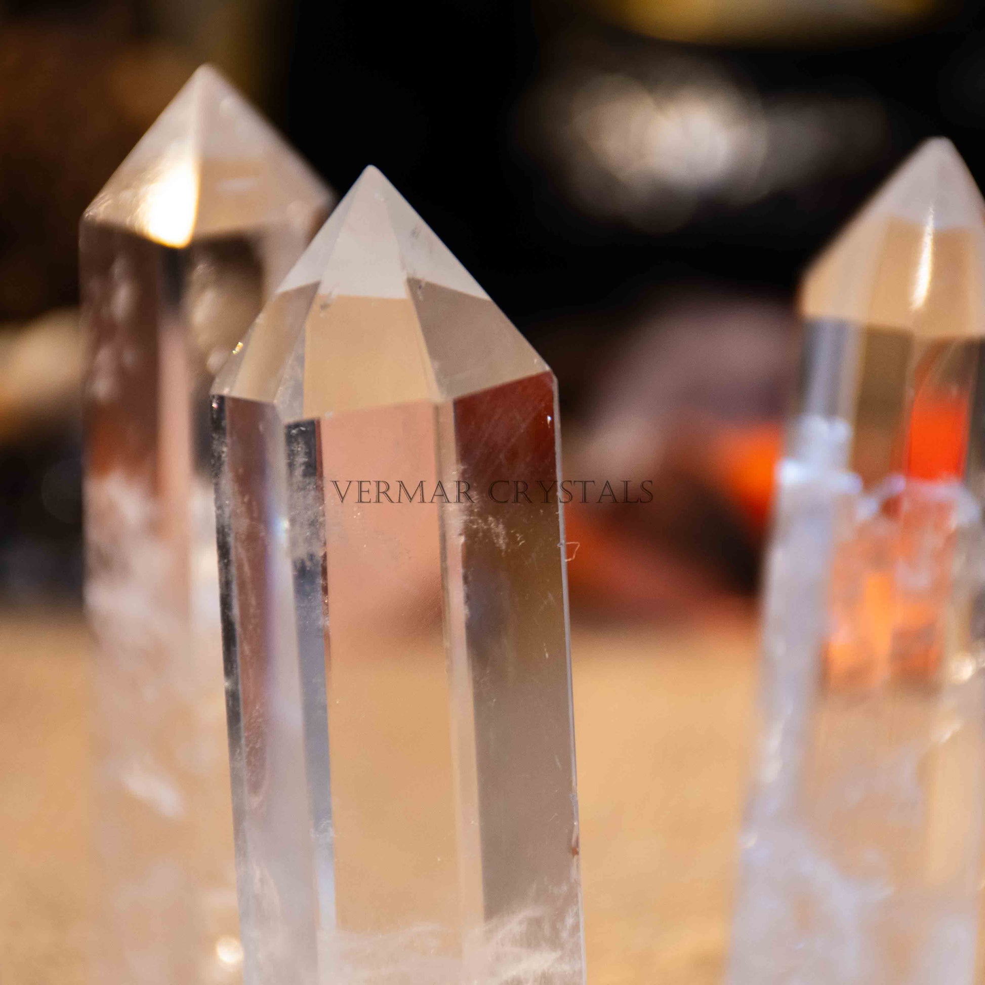 Three natural clear quartz towers with pointed tips standing upright on blurred warm background